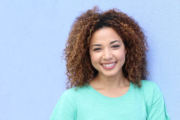 Latin girl with blond Afro hair style smiling portrait on a blue background with copy space