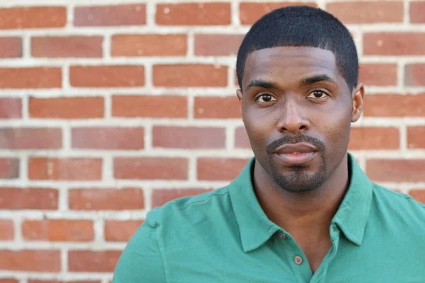 Good looking male manager in green polo on brick wall background with copy space