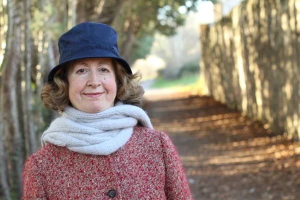 Olgun bir kadın gündüz vakti parkta duruyor.