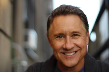 Yakışıklı, olgun bir adamın sokakta çekilmiş yakın plan portresi.