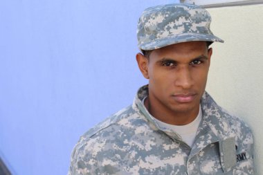 Mavi duvarın önünde üniformalı yakışıklı Afro-Amerikan askerinin yakın plan portresi