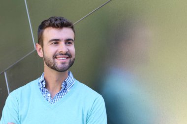 İşaretli gömlekli genç bir adam portresi ve kolları çapraz duran cyan süveter.