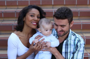 Yeni doğmuş bebeklerine sarılan ırklar arası bir çift.