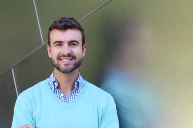 İşaretli gömlekli genç bir adam portresi ve kolları çapraz duran cyan süveter.