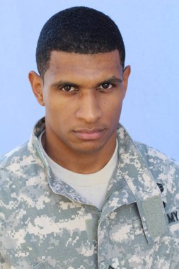 Mavi duvarın önünde üniformalı yakışıklı Afro-Amerikan askerinin yakın plan portresi