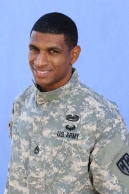 Mavi duvarın önünde üniformalı yakışıklı Afro-Amerikan askerinin yakın plan portresi