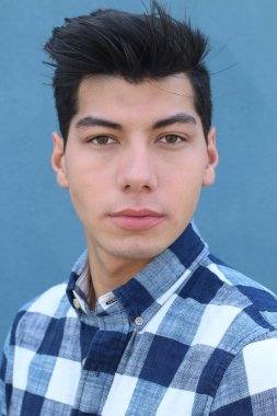 Mavi duvarın önünde poz veren yakışıklı genç adamın yakın plan portresi.