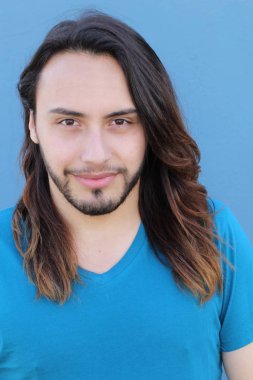 Mavi duvarın önünde uzun saçlı yakışıklı genç adamın yakın plan portresi.