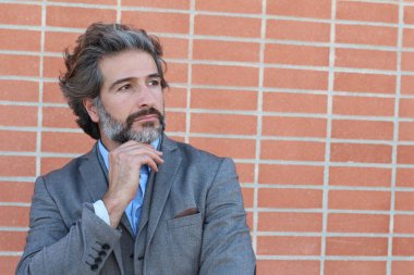 Duvarın önünde gri takım elbiseli yakışıklı bir iş adamının yakın plan portresi.