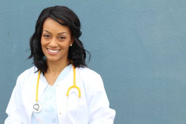 Dost canlısı, güler yüzlü, Afro-Amerikan, laboratuvar önlüğü ve steteskobu olan bir kadının portresi. Hastane kliniği mavi arka plan