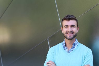 İşaretli gömlekli genç bir adam portresi ve kolları çapraz duran cyan süveter.