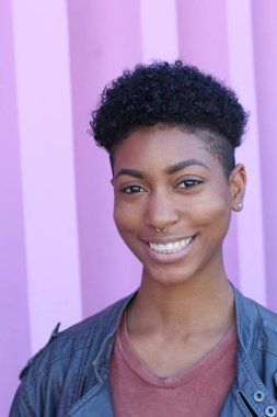 Mor duvar arkasında kısa kıvırcık saçlı güzel bir Afrikalı kadının yakın plan portresi. 
