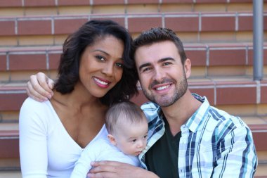 Yeni doğmuş bebeklerine sarılan ırklar arası bir çift.