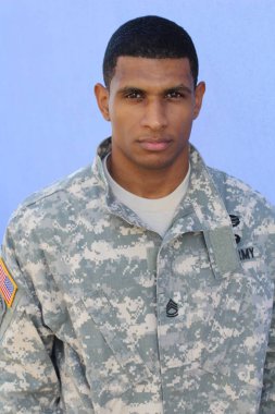 Mavi duvarın önünde üniformalı yakışıklı Afro-Amerikan askerinin yakın plan portresi