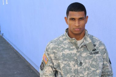 Mavi duvarın önünde üniformalı yakışıklı Afro-Amerikan askerinin yakın plan portresi