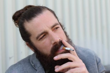 Sigara içen yakışıklı sakallı adamın portresi. Erkek saçı olan hippi..