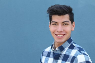 Mavi duvarın önünde poz veren yakışıklı genç adamın yakın plan portresi.