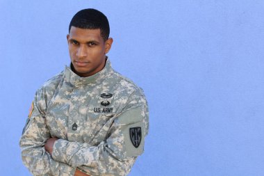 Mavi duvarın önünde üniformalı yakışıklı Afro-Amerikan askerinin yakın plan portresi