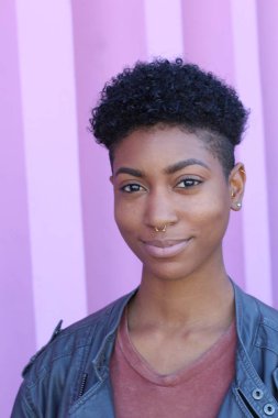 Mor duvar arkasında kısa kıvırcık saçlı güzel bir Afrikalı kadının yakın plan portresi. 