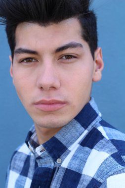 Mavi duvarın önünde poz veren yakışıklı genç adamın yakın plan portresi.