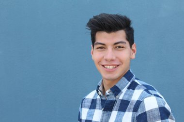 Mavi duvarın önünde poz veren yakışıklı genç adamın yakın plan portresi.