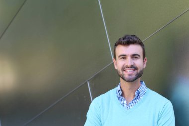 İşaretli gömlekli genç bir adam portresi ve kolları çapraz duran cyan süveter.