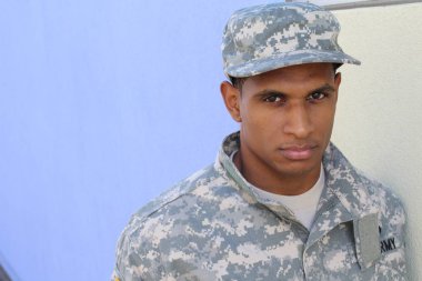 Mavi duvarın önünde üniformalı yakışıklı Afro-Amerikan askerinin yakın plan portresi