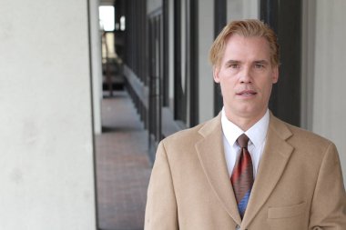 Sokakta bej takım elbiseli yakışıklı bir adamın yakın plan portresi.