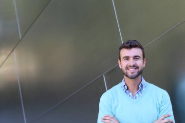 İşaretli gömlekli genç bir adam portresi ve kolları çapraz duran cyan süveter.