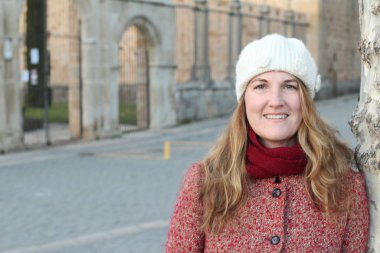 Kış giysileri içinde gülen sarışın kadının portresi gündüz vakti parkta duruyor.