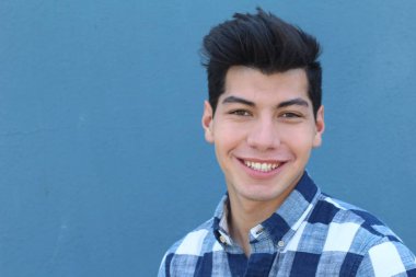 Mavi duvarın önünde poz veren yakışıklı genç adamın yakın plan portresi.