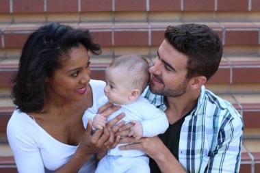 Yeni doğmuş bebeklerine sarılan ırklar arası bir çift.