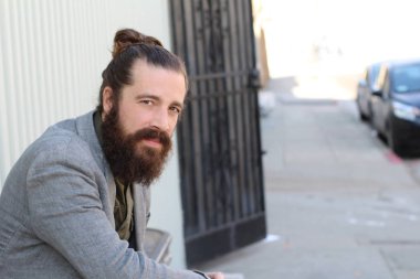 Tarz sahibi sakallı hippi modeli. Erkek saç stili, sokakta yaşam tarzı, tarlanın derinliği.