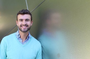 İşaretli gömlekli genç bir adam portresi ve kolları çapraz duran cyan süveter.