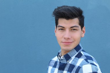 Mavi duvarın önünde poz veren yakışıklı genç adamın yakın plan portresi.