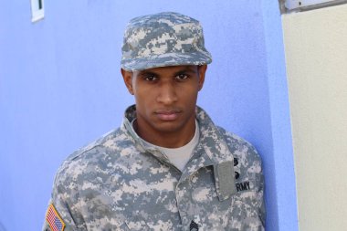 Mavi duvarın önünde üniformalı yakışıklı Afro-Amerikan askerinin yakın plan portresi