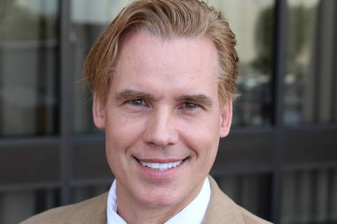 Sokakta bej takım elbiseli yakışıklı bir adamın yakın plan portresi.