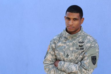 Mavi duvarın önünde üniformalı yakışıklı Afro-Amerikan askerinin yakın plan portresi