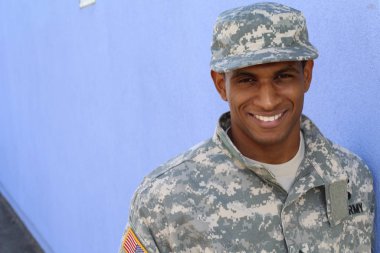 Mavi duvarın önünde üniformalı yakışıklı Afro-Amerikan askerinin yakın plan portresi