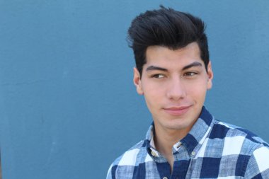 Mavi duvarın önünde poz veren yakışıklı genç adamın yakın plan portresi.