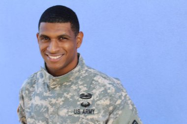 Mavi duvarın önünde üniformalı yakışıklı Afro-Amerikan askerinin yakın plan portresi