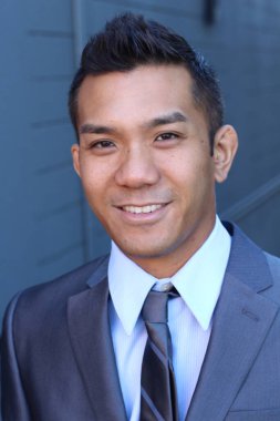 Mavi duvarın önünde, melez bir ırkın yakışıklı genç işadamının yakın plan portresi.