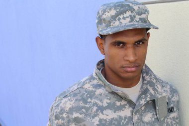Mavi duvarın önünde üniformalı yakışıklı Afro-Amerikan askerinin yakın plan portresi