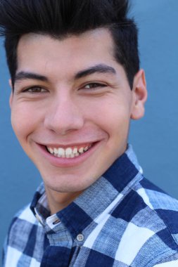 Mavi duvarın önünde poz veren yakışıklı genç adamın yakın plan portresi.