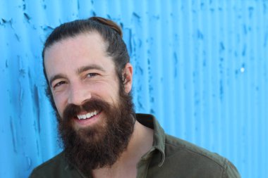 Tarz sahibi sakallı hippi erkek saç stili, sokakta yaşam tarzı, tarlanın derinliği. Mavi arkaplan