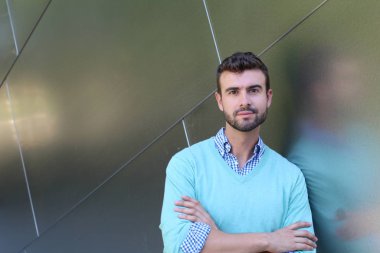 İşaretli gömlekli genç bir adam portresi ve kolları çapraz duran cyan süveter.