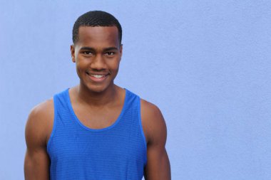 Mavi duvarın önündeki yakışıklı Afrikalı Amerikalı genç adamın yakın plan portresi.