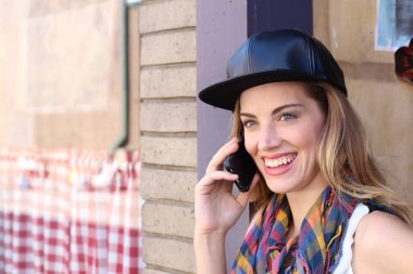 Güler yüzlü sarışın kız şehir dışında telefon kullanıyor.