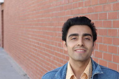 Kırmızı tuğla duvarın arka planında iyi bir adamın yakın plan portresi.