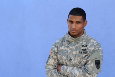 Mavi duvarın önünde üniformalı yakışıklı Afro-Amerikan askerinin yakın plan portresi